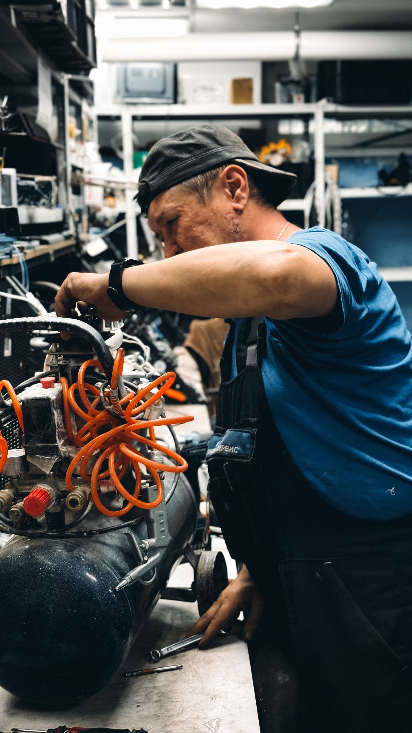 Monteur werkt aan een compressor met persluchtslangen in een werkplaats