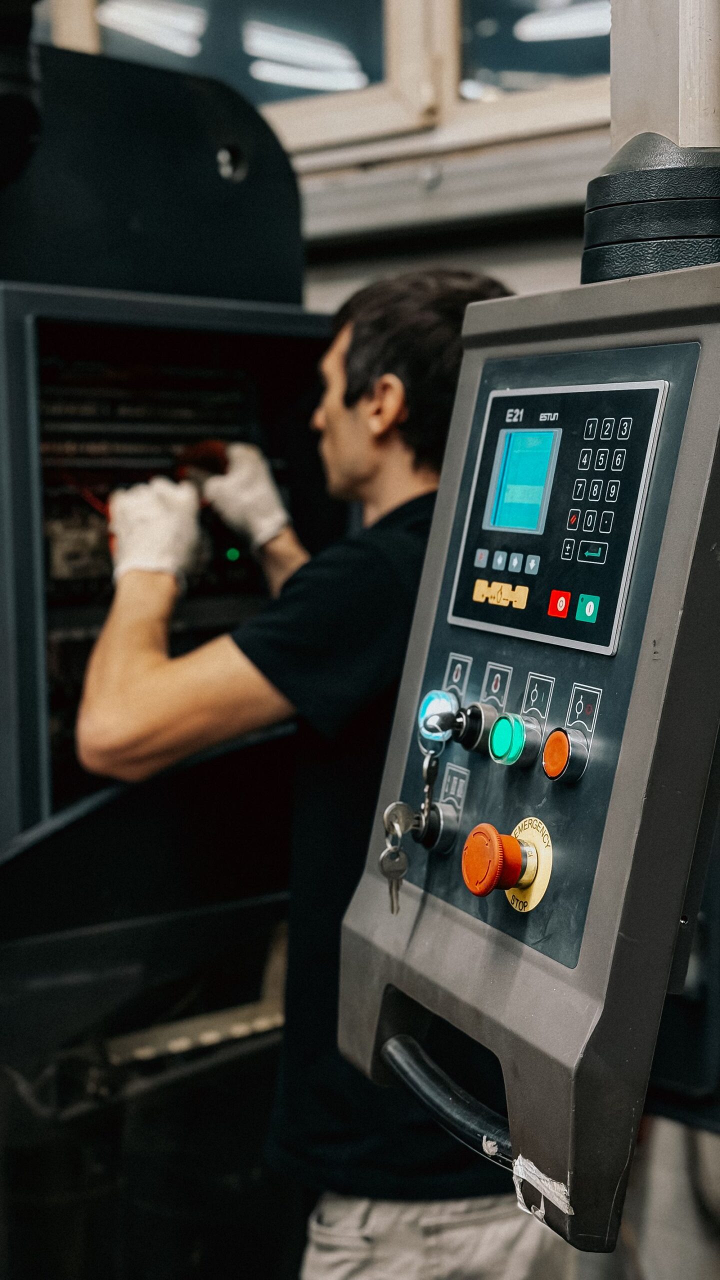 Technicus bedient het controlepaneel van een productiemachine in een fabriek