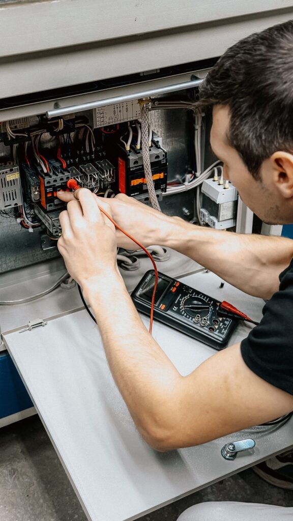 Technicus diagnosticeert een elektrische schakelkast met een multimeter
